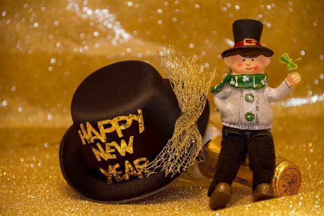 celebrate: happy new year black top hat with a figurine and a gold background