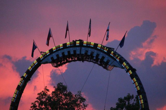 Bluegrass Fair: a rollercoaster during dusk with a pink sky