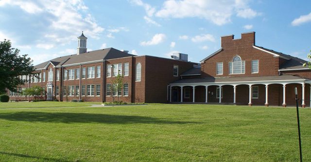 Paul Miller Ford: view of a high shool building with green grass and blue skies